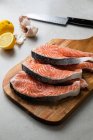 Steaks de poisson frais sur planche de bois — Photo de stock