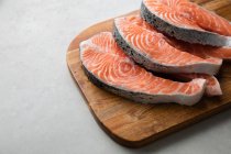 Fresh fish steaks on wooden board — Stock Photo