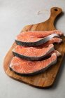 Steaks de poisson frais sur planche de bois — Photo de stock