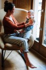 Mother with baby sitting near window — Stock Photo