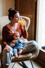 Обрізати матір з соком і дитиною, відпочиваючи на стільці — стокове фото