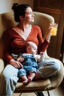 Урожай мать с соком и ребенок отдыхает на стуле — стоковое фото