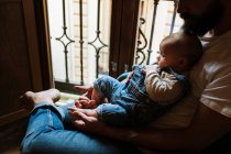 Pai barbudo com bebê sentado perto da janela — Fotografia de Stock