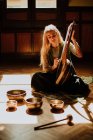 Frau spielt Leier in der Nähe tibetischer Schalen — Stockfoto
