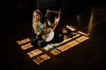 Mulher tocando lira no quarto escuro — Fotografia de Stock