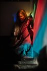 Femme jouant lyre sous la lumière colorée — Photo de stock