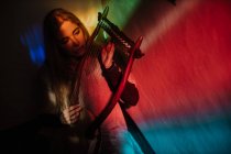 Woman playing lyre under colorful light — Stock Photo