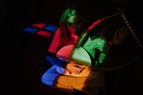 Femme jouant lyre sous la lumière colorée — Photo de stock