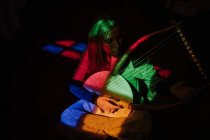 Mulher tocando lira sob luz colorida — Fotografia de Stock