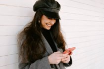 Щаслива жінка використовує смартфон біля стіни — стокове фото