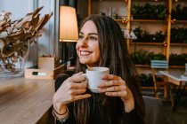 Задоволена жінка п'є каву в кафе — стокове фото