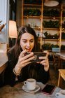 Молода жінка використовує смартфон у кафе — стокове фото