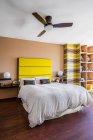 Komfortables Bett mit leuchtend gelbem Kopfteil in modernem Studio-Apartment im minimalistischen Stil eingerichtet — Stockfoto