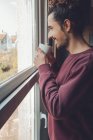 Adult male with mug looking out window — Stock Photo