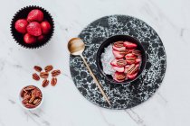 Draufsicht auf leckeres Sorbet mit frischen Erdbeeren und Walnüssen, serviert in Schüssel auf Marmortisch in der Nähe von Löffel — Stockfoto