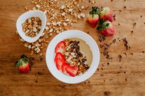 Nahaufnahme Schüssel mit leckerem süßem Püree mit Erdbeeren und Schokolade ergänzt mit Erdnüssen und Walnüssen und serviert zum Frühstück — Stockfoto