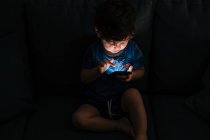 Neugieriger kleiner Junge surft zu Hause mit dem Smartphone — Stockfoto