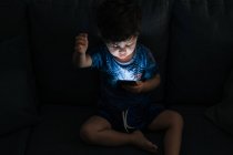 Curieux petit garçon naviguant smartphone à la maison — Photo de stock