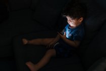 Niño curioso navegando teléfono inteligente en casa - foto de stock