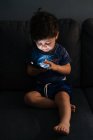 Любопытный маленький мальчик просматривает смартфон дома — стоковое фото