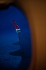 Blick aus dem Fenster auf den Flügel eines modernen Flugzeugs, das in dunkler Nacht über Wolken fliegt — Stockfoto