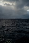 Acqua di mare con uccelli che volano in cielo grigio nuvoloso contro la costa montana innevata in inverno in Norvegia — Foto stock