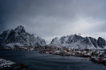 De cima do porto de cidade contra cumes montanhosos nevados no horizonte no tempo nublado na Noruega — Fotografia de Stock