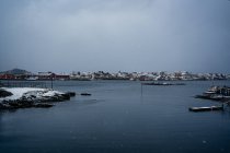 Desde arriba del puerto de la ciudad contra las cordilleras nevadas en el horizonte en tiempo nublado en Noruega - foto de stock
