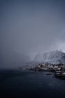 Desde arriba del puerto de la ciudad contra las cordilleras nevadas en el horizonte en tiempo nublado en Noruega - foto de stock