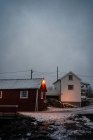 Chalet à rayures rouge foncé avec fenêtres blanches et toit enneigé dans une petite ville par temps couvert à Lofoten — Photo de stock