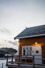Maisons de campagne jaunes sur la côte du détroit contre les crêtes de montagne enneigées brumeuses par temps couvert en Norvège — Photo de stock