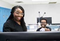 Mujeres negras y hombres uniformados discutiendo datos sobre computadoras mientras trabajan juntos en un laboratorio contemporáneo - foto de stock