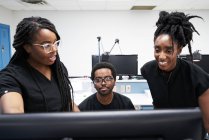 Les femmes noires et l'homme en uniforme discutent des données informatiques tout en travaillant dans un laboratoire contemporain ensemble — Photo de stock