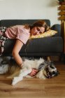 Seitenansicht einer erwachsenen Frau, die einen lustigen Collie berührt, während sie zu Hause auf einem bequemen Sofa schläft — Stockfoto