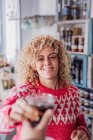 Glücklich lockiges Haar blonde Verkäuferin Barkeeper mit Glas Tasse mit Wein während der Arbeit in lokalen Feinkost Lebensmittelgeschäft — Stockfoto