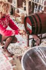 Свыше анонимный продавец наполняет стакан вином из бочки во время работы в местном продуктовом магазине — стоковое фото