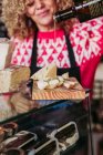 Доросла жінка в фартусі нарізає свіжий сир під час роботи в затишному місцевому продуктовому магазині — стокове фото