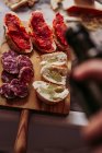 Von oben leckere Wurststücke und Brotscheiben mit köstlicher Sauce auf Holzbrett im örtlichen Lebensmittelladen — Stockfoto