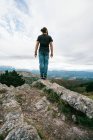 Homme méconnaissable marchant sur une colline dans la nature — Photo de stock