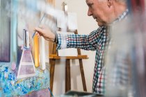 У віці чоловік малює картину пензлем — стокове фото