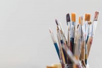 Many paintbrushes in glass on table — Stock Photo