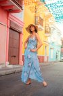 Mulher elegante em roupa de verão em pé perto de edifício colorido — Fotografia de Stock