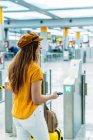 Passager féminin en tenue à la mode debout à côté du comptoir d'enregistrement à l'aéroport — Photo de stock