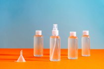 Vários frascos claros com gel clorídrico junto com um funil para encher serve para desinfetar as mãos de covid-19 — Fotografia de Stock