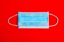 Blue single-use mask for virus protection on red background — Stock Photo