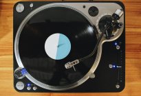 Ansicht von zeitgenössischem Plattenspieler mit Retro-Disc auf Holztisch im Wohnzimmer — Stockfoto