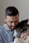 Mann im lässigen Outfit umarmt und küsst geliebten Border Collie Hund zu Hause — Stockfoto