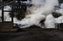 Кучи кокса, излучающие густой дым после процесса охлаждения холодной водой на утолщающей башне коксохимической установки — стоковое фото