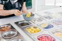 Anonymous mature woman choosing delicious fruit from metal containers while self servicing in contemporary restaurant — Stock Photo