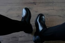 Pés masculinos em casual limpo par de botas pretas no chão de madeira — Fotografia de Stock